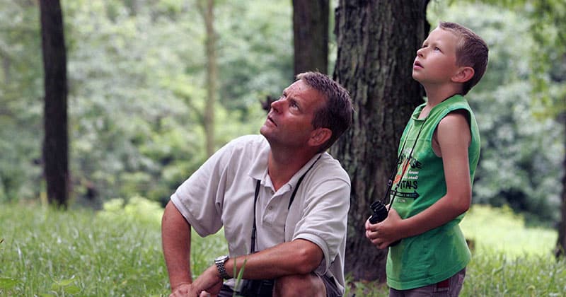 Father and son bird watching in the forest
